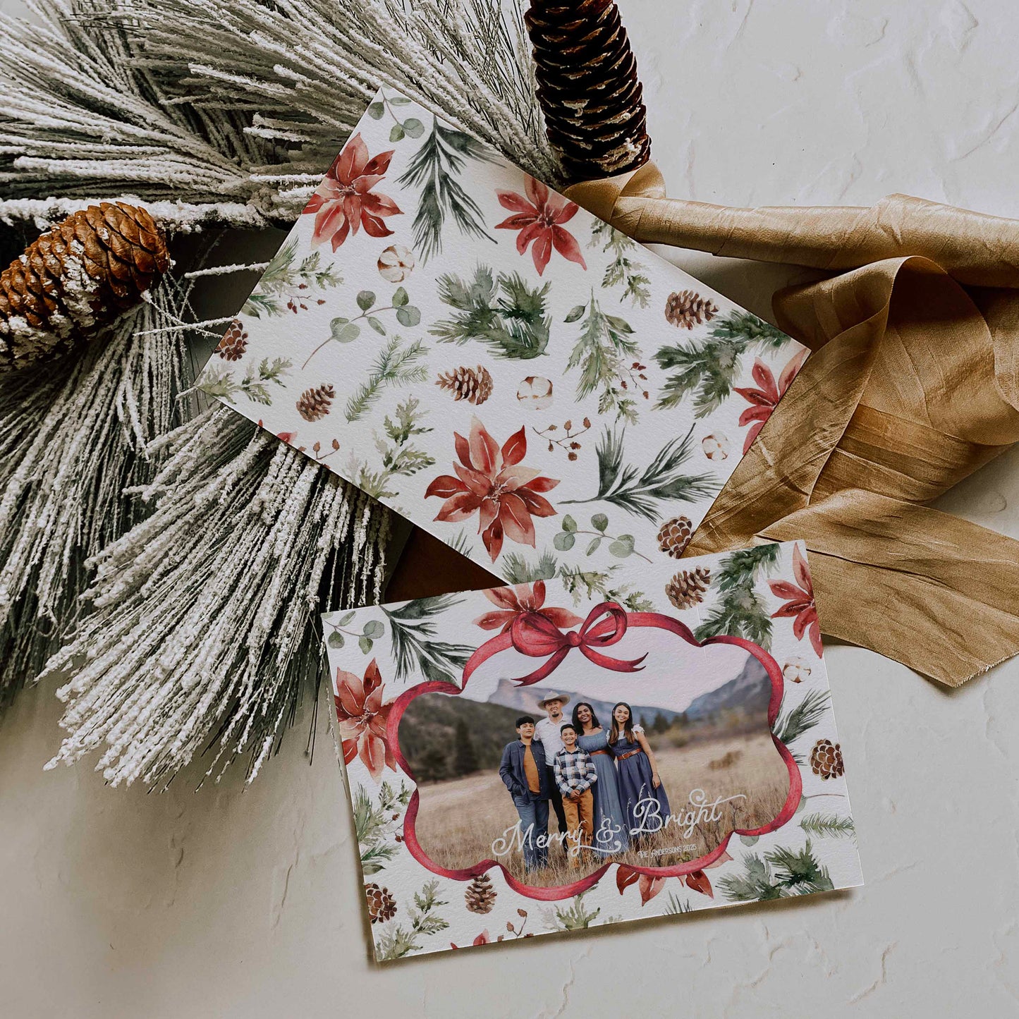 Two Christmas-themed cards with floral designs and a family photo on a white surface with decorative elements.