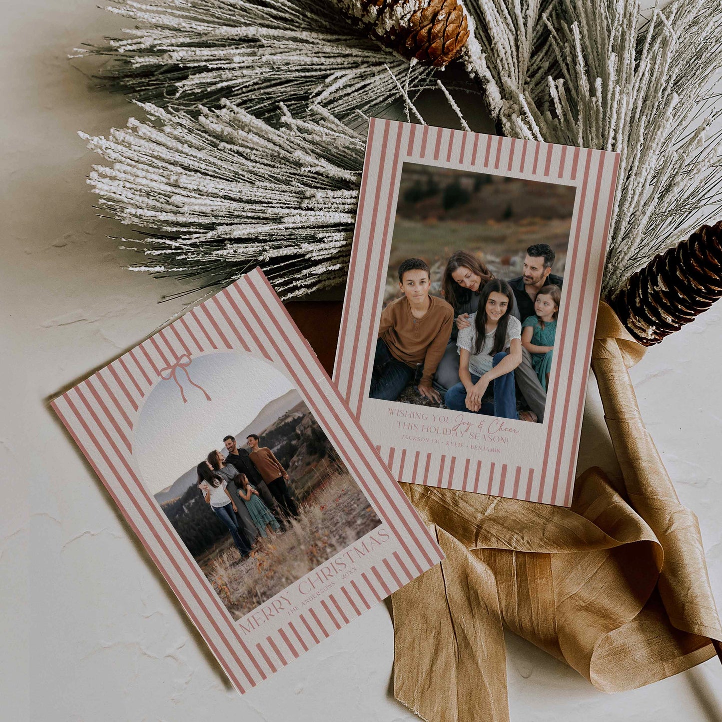 Christmas cards with striped borders featuring family photos, surrounded by decorative elements on a light surface.