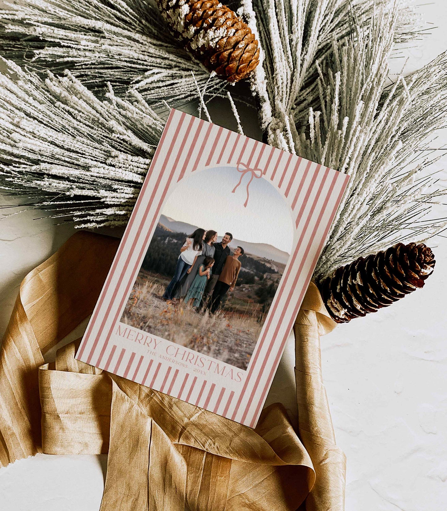 Christmas card with a photo of a family and pinecones and dried grasses on a white surface