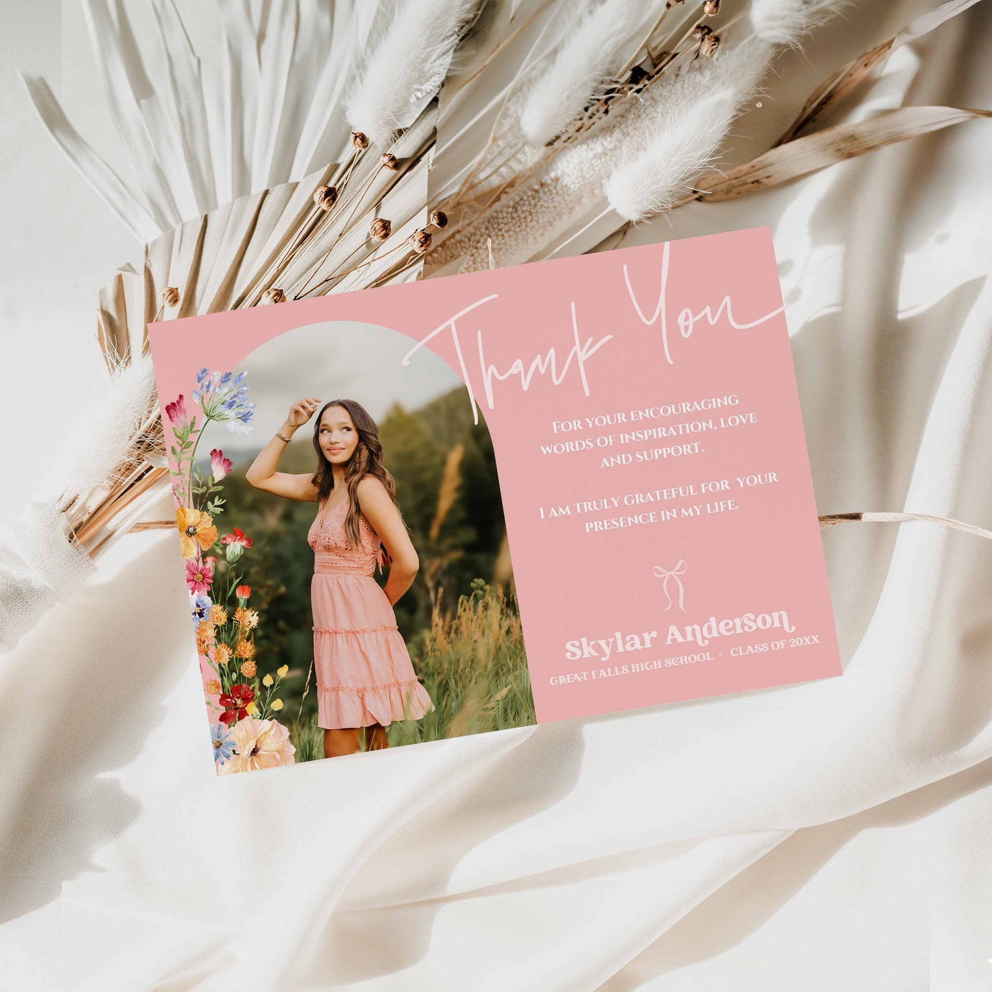 Graduation thank you card with arched photo of a woman in a pink dress on a white background with dried plants.