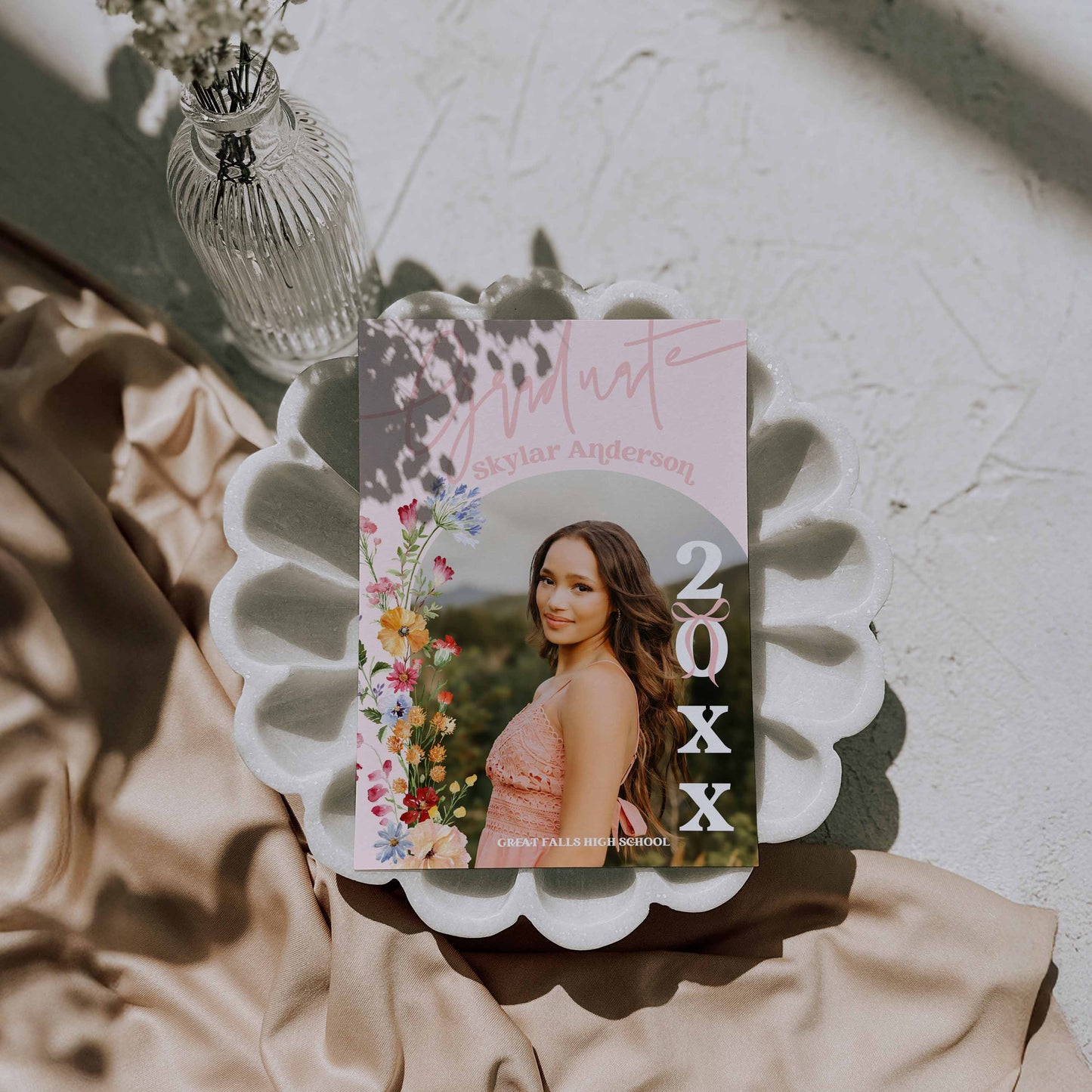 Graduation invitation card with floral design and photo of a woman on a decorative plate.