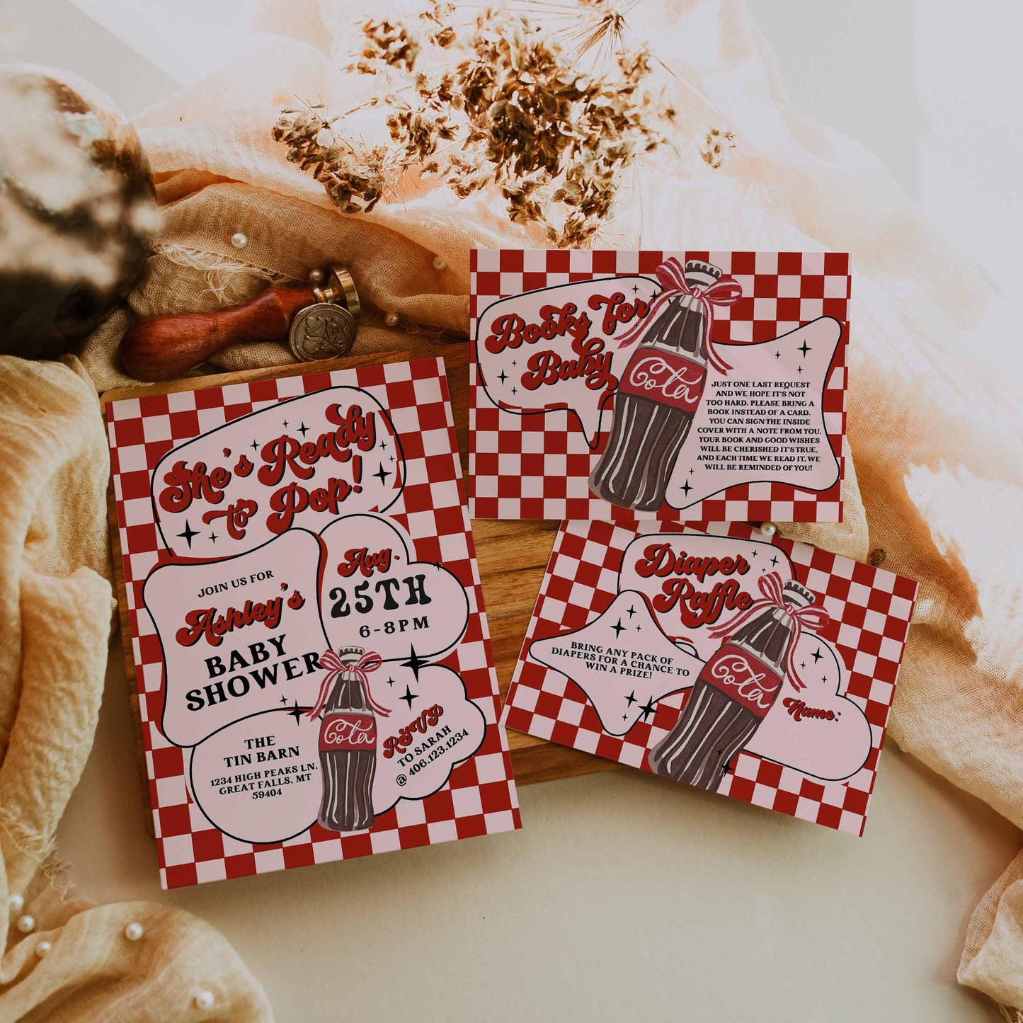 Red and white baby shower invitations with checkered pattern on a rustic background.