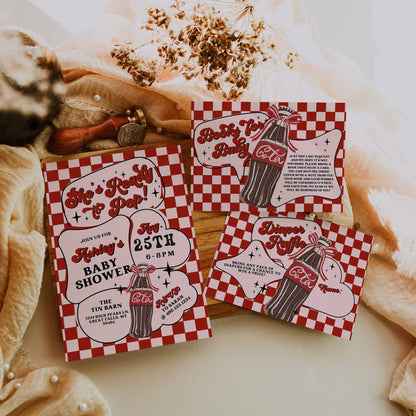 Red and white baby shower invitations with checkered pattern on a rustic background.