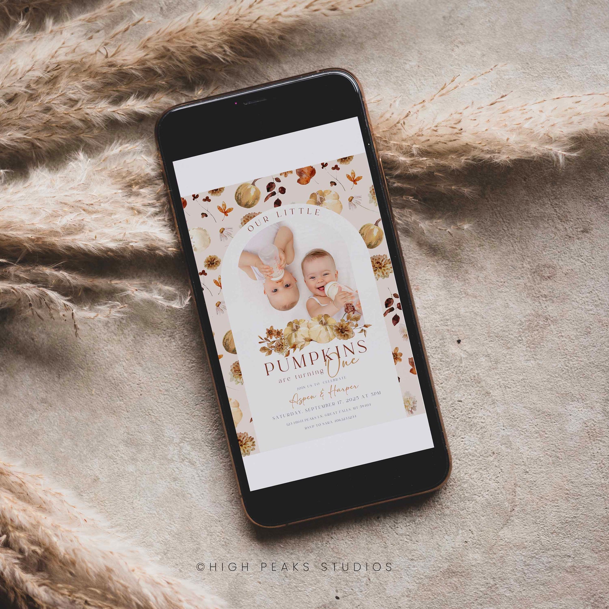 Phone displaying a Editable Our Little Pumpkins Twin Birthday Invitation Photo By High Peaks Studios on a textured surface