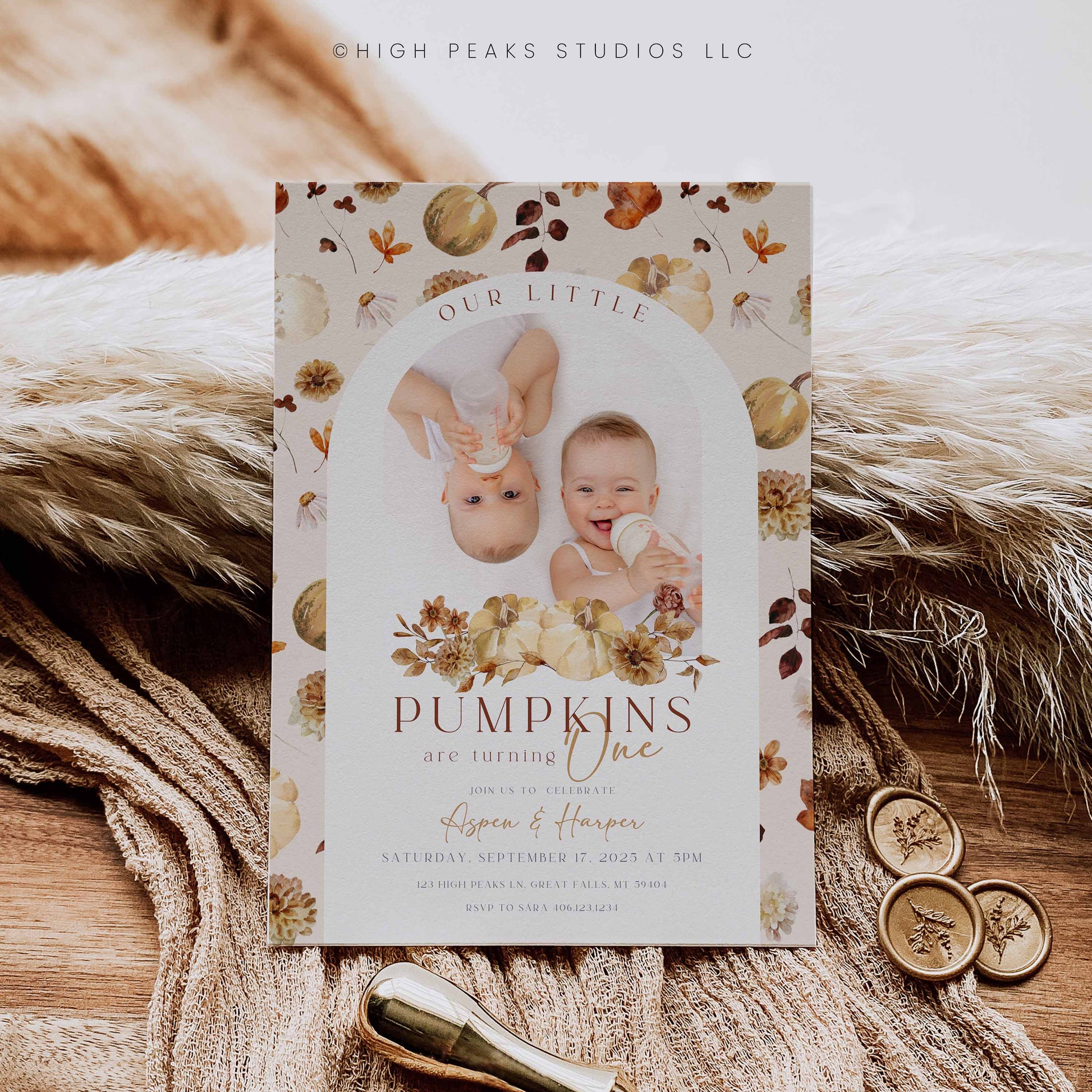 Invitation card with two babies and autumn-themed design on a textured surface.