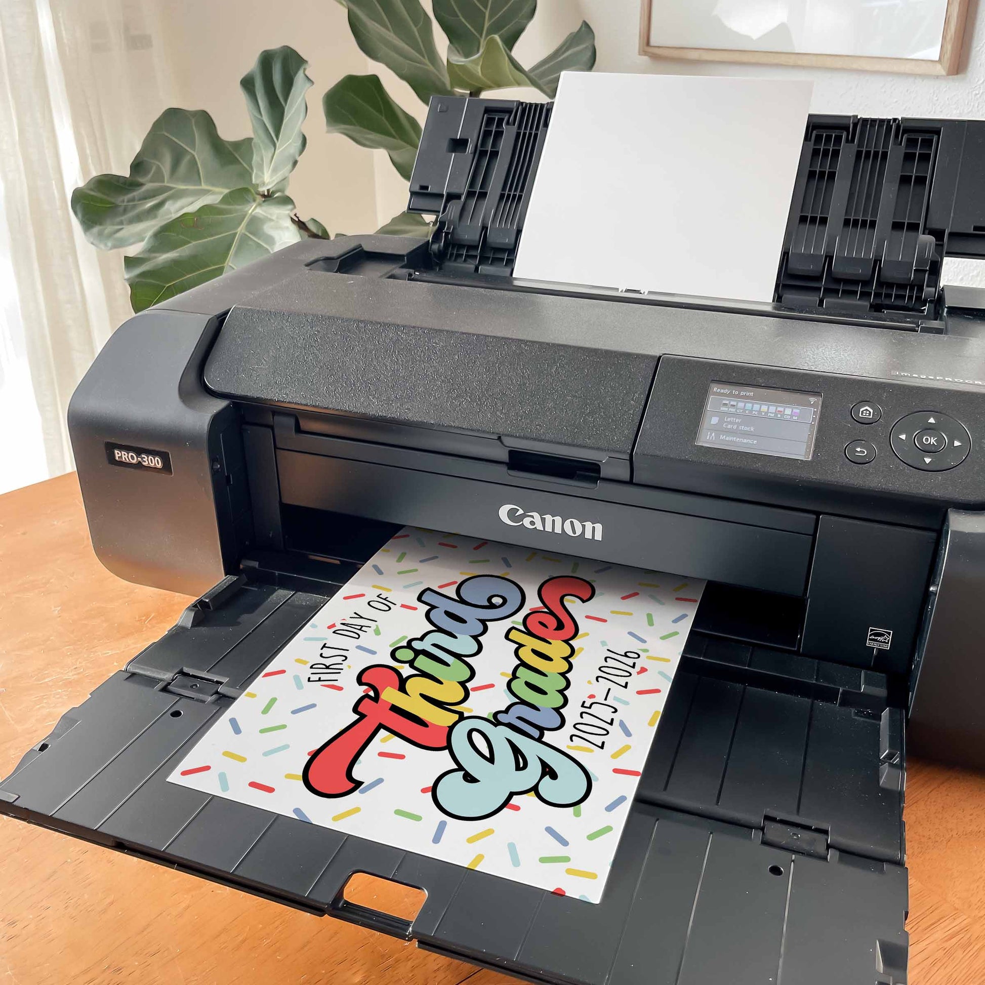 Canon printer printing a colorful back to third grade school sign with text on a wooden table. By High Peaks Studios